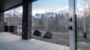 A modern building with stone pillars, a glass door, and a view of mountains. - Canmore center 5BR+4.5BTH Mt view private hot tub (Canmore)