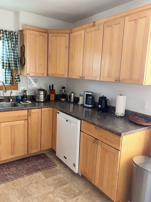 Eine Küche mit Holzschränken, einem Geschirrspüler, einer Kaffeemaschine und einem Wasserkocher.