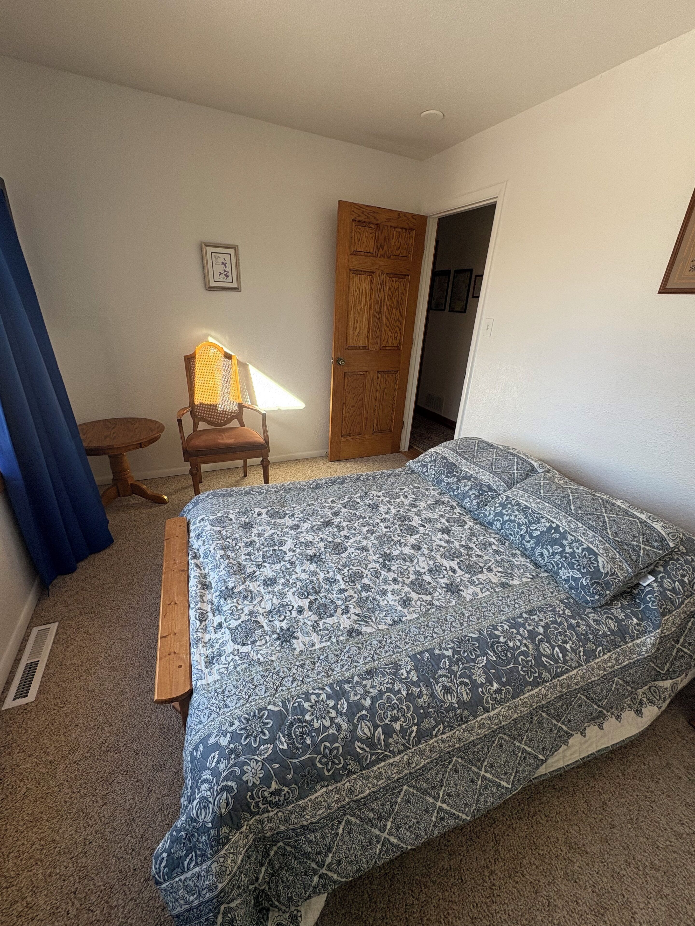 Ein Schlafzimmer mit einem Bett, einem Sessel, einer Tür und einem kleinen Tisch.