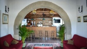 A lobby with a bar area, red sofas, and potted plants. - Hotel Restaurant la Mecedora (Manilva)