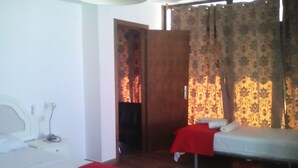 A hotel room with two single beds, each with a red bedspread and white pillows. There is a wooden floor and a white wall with a small white object on the left side. - Hotel Restaurant la Mecedora (Manilva)