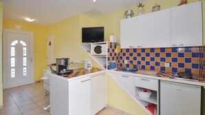 Een kleine keuken met een magnetron, koffiezetapparaat en een klein spoelbakje.