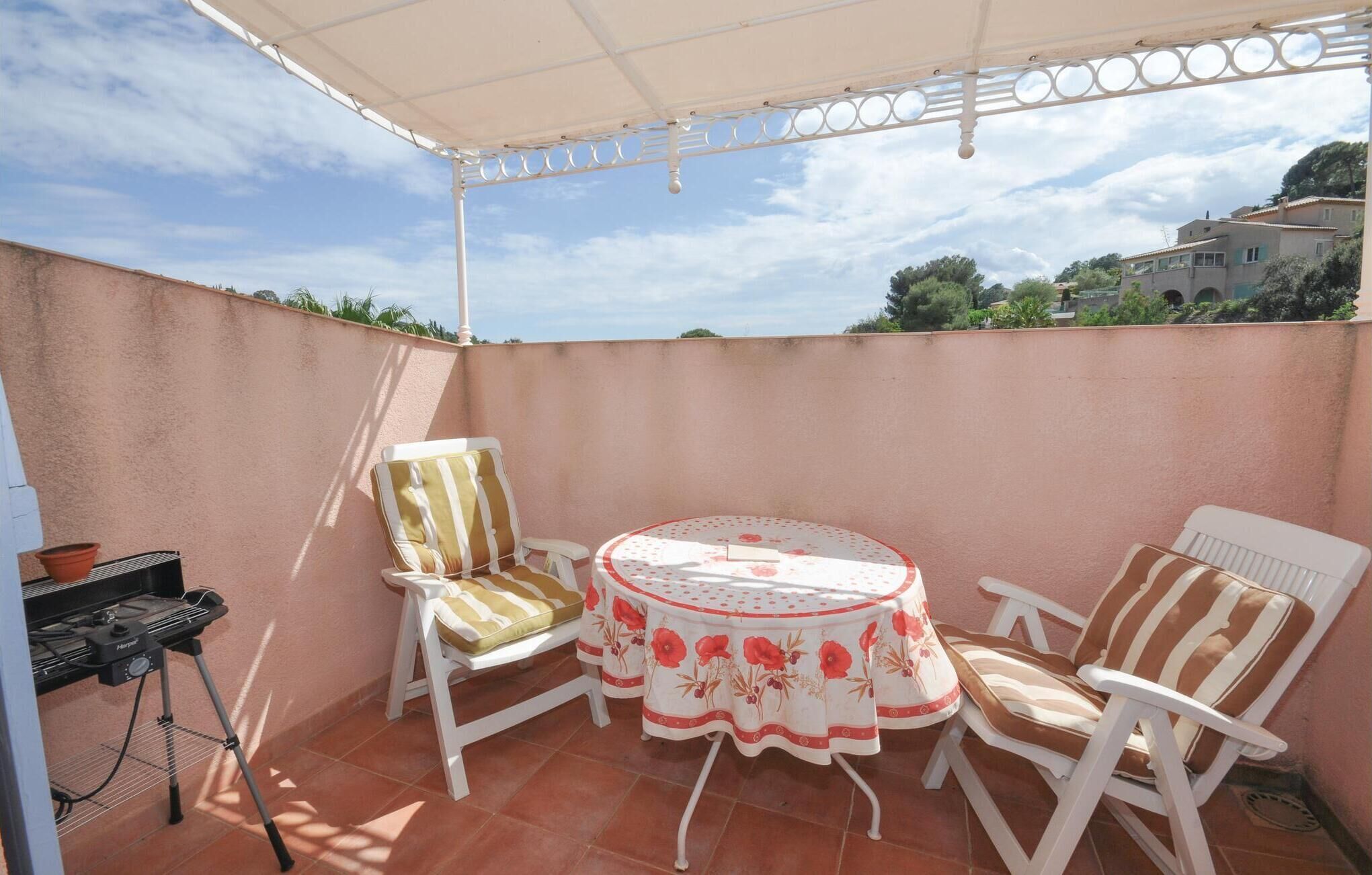 A patio with a round table, two chairs, and a barbecue grill.