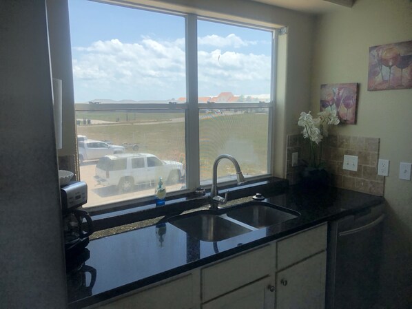 A kitchen with a large window, a sink, and a countertop.