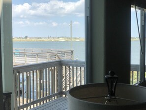 A view from a window overlooking a wooden dock and a body of water, with a lamp on the windowsill.