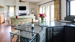A spacious kitchen with a central island, a dining area, and a fireplace. - The Farmhouse at Veritas (Afton)