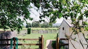 A rural property with a wooden fence, a small shed, and a gravel path leading to a gate. - The Farmhouse at Veritas (Afton)