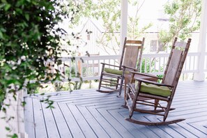 A wooden porch with two rocking chairs and a white fence. - The Farmhouse at Veritas (Afton)