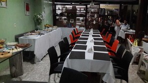 A dining area with multiple tables and chairs, some covered with white tablecloths and others with black and white checkered tablecloths. - Pousada Girassol (Rio das Ostras)