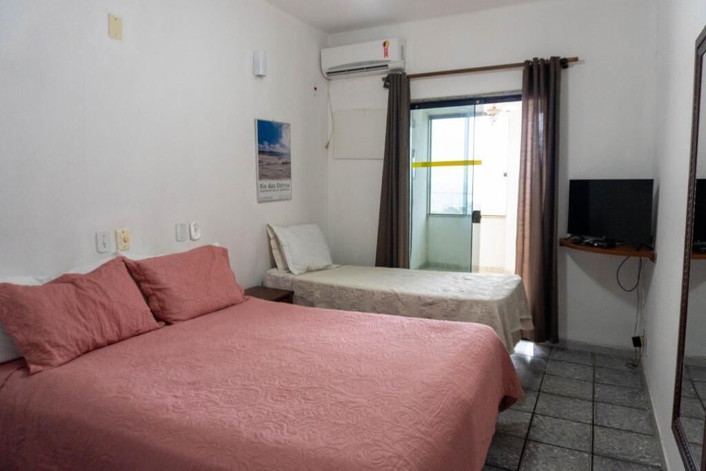 A hotel room with a bed, a small table, a television, and a window with curtains.