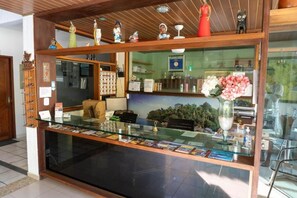 A reception desk with a glass partition, a wooden counter, and various decorative items.