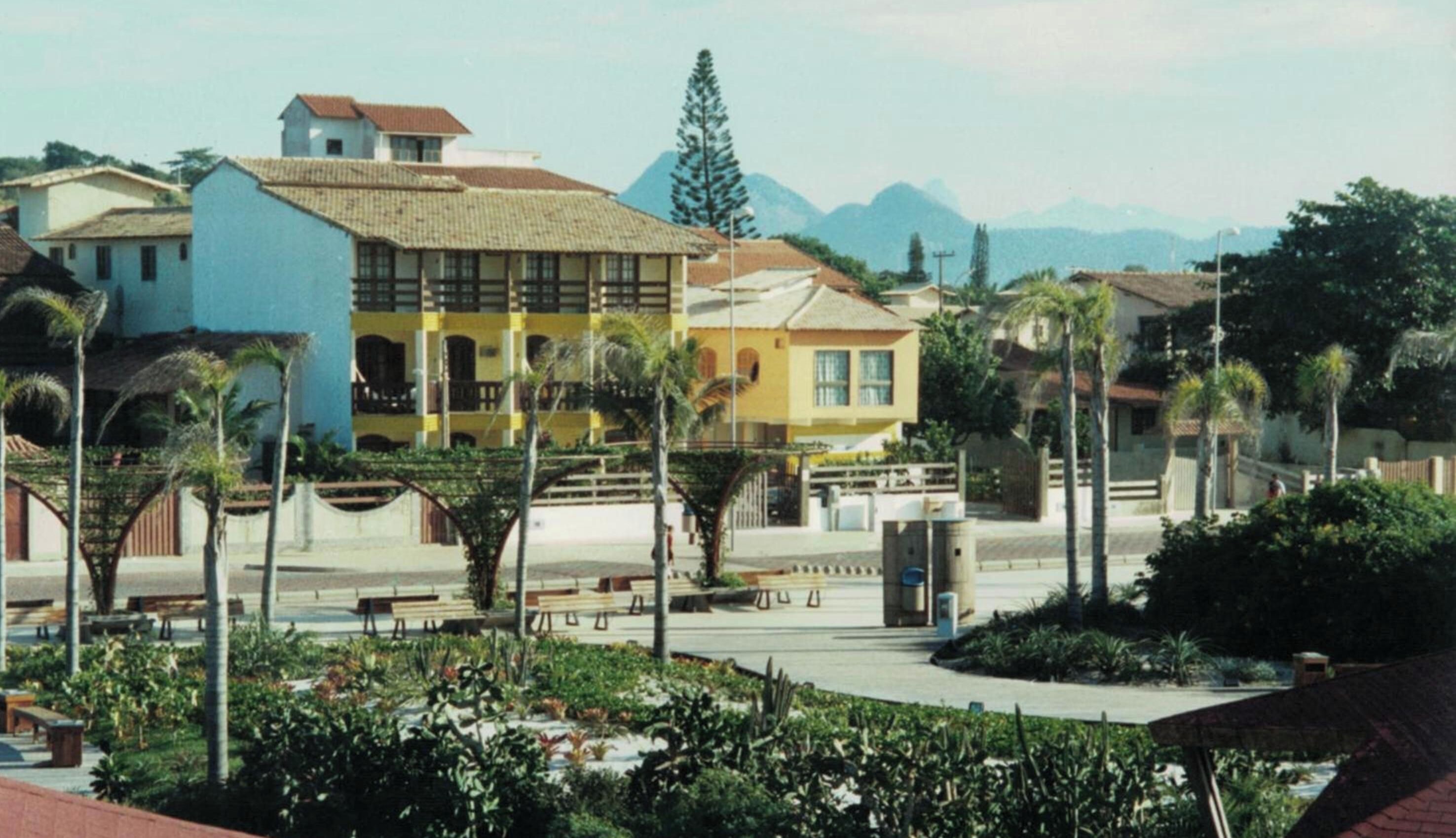 Área residencial com um edifício amarelo de destaque, um edifício azul e uma cadeia montanhosa ao fundo.