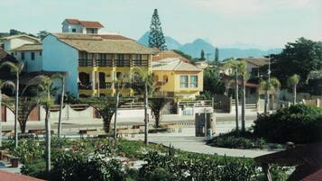 Área residencial com um edifício amarelo de destaque, um edifício azul e uma cadeia montanhosa ao fundo.