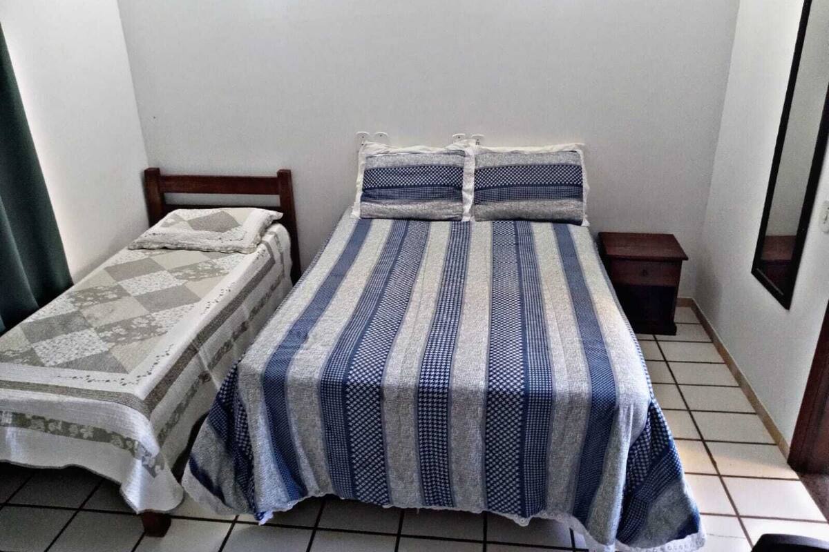 Un petit logement composé d’une seule pièce, comprenant un lit, une table de chevet et un miroir.