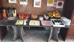 A buffet table with various food items and condiments. - Pousada Girassol (Rio das Ostras)