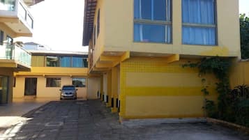 Um edifício amarelo com duas janelas e um carro estacionado na frente.