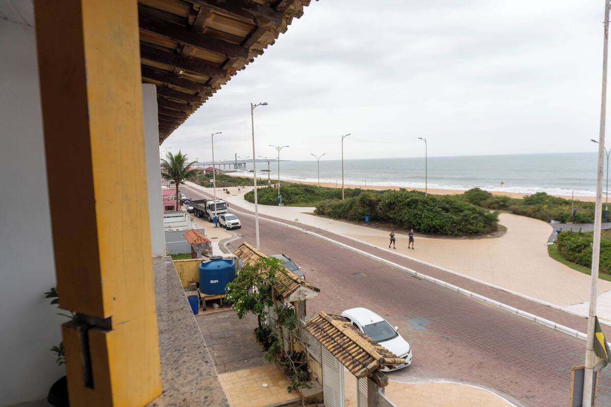 Une route côtière offrant une vue sur la plage, avec un chemin piétonnier et des voitures garées.