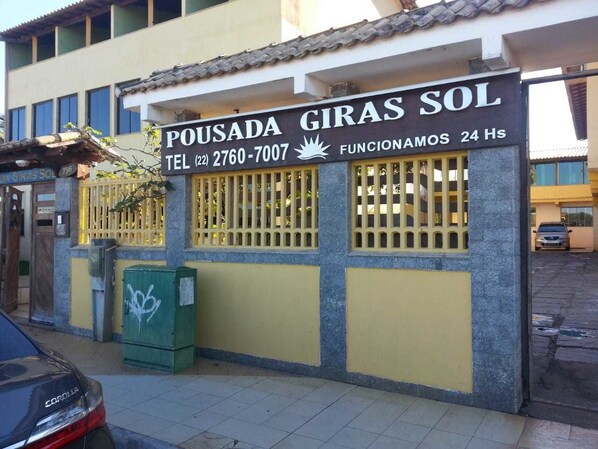 A building with a sign reading "POUSADA GIRAS SOL" and a phone number. - Pousada Girassol (Rio das Ostras)