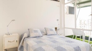 A bedroom with a bed, two bedside tables, a window, and an air conditioning unit. - Luminoso Duplex en Recoleta (Buenos Aires)