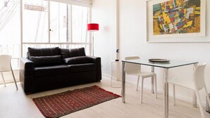 A modern living room with a black sofa, a glass dining table, and a red floor lamp. - Luminoso Duplex en Recoleta (Buenos Aires)