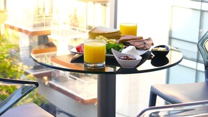 A breakfast tray with orange juice, toast, and a bowl of cereal on a glass table in a hotel room with a view of a building. - Alife Apart Hotel (Beirut)