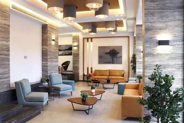 A modern living room with a sofa, armchairs, coffee tables, and a fireplace.