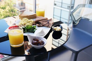 A breakfast setting with toast, scrambled eggs, tomatoes, and a glass of orange juice on a table.
