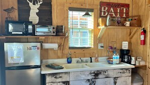 Una cocina rústica con armarios de madera, microondas, tostadora, lavaplatos y cafetera.