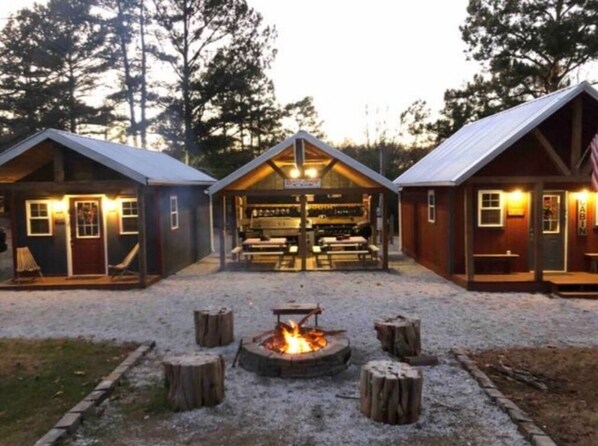 Enjoy meals around the fire pit in the central dining area, surrounded by rustic benches and tables.