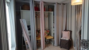 Una habitación con armario, una silla y una pequeña mesa con cojín.