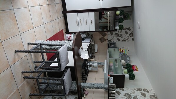 A kitchen with a dining area, featuring a dining table, chairs, a refrigerator, and a microwave.