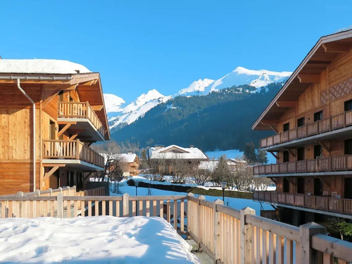 A wooden chalet with balconies overlooking a snowy mountain landscape.