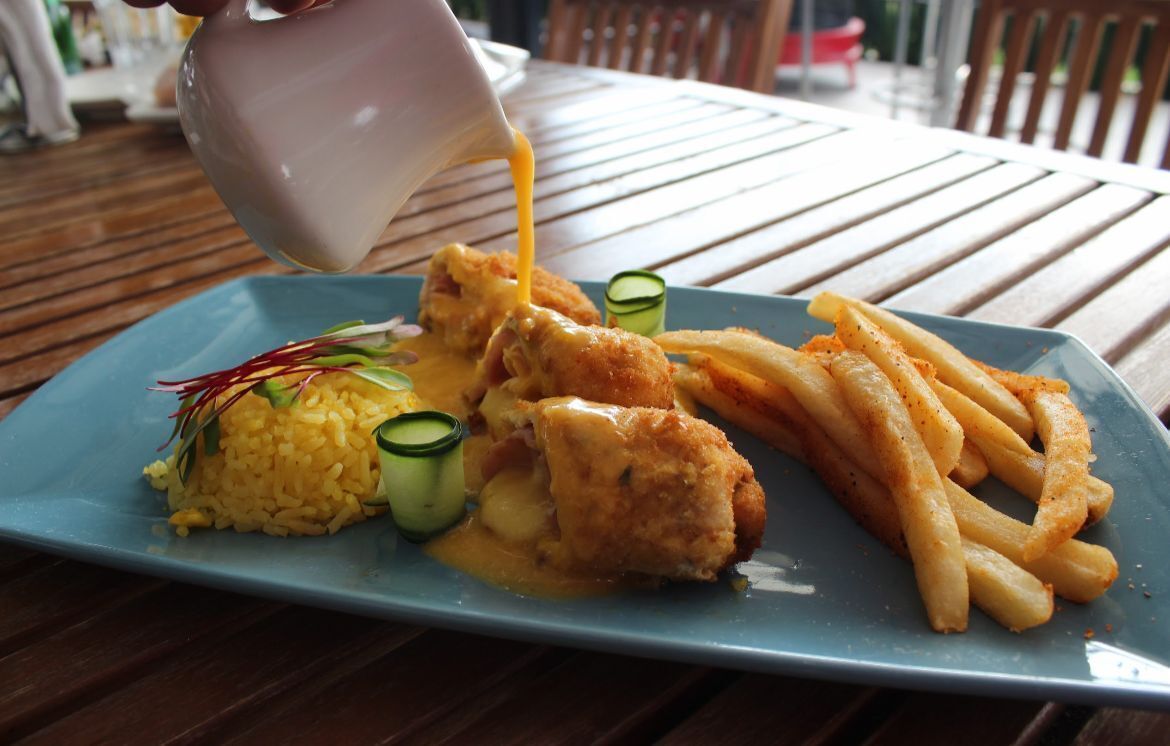 Un plato con pollo frito, papas fritas y arroz, cubierto con salsa.
