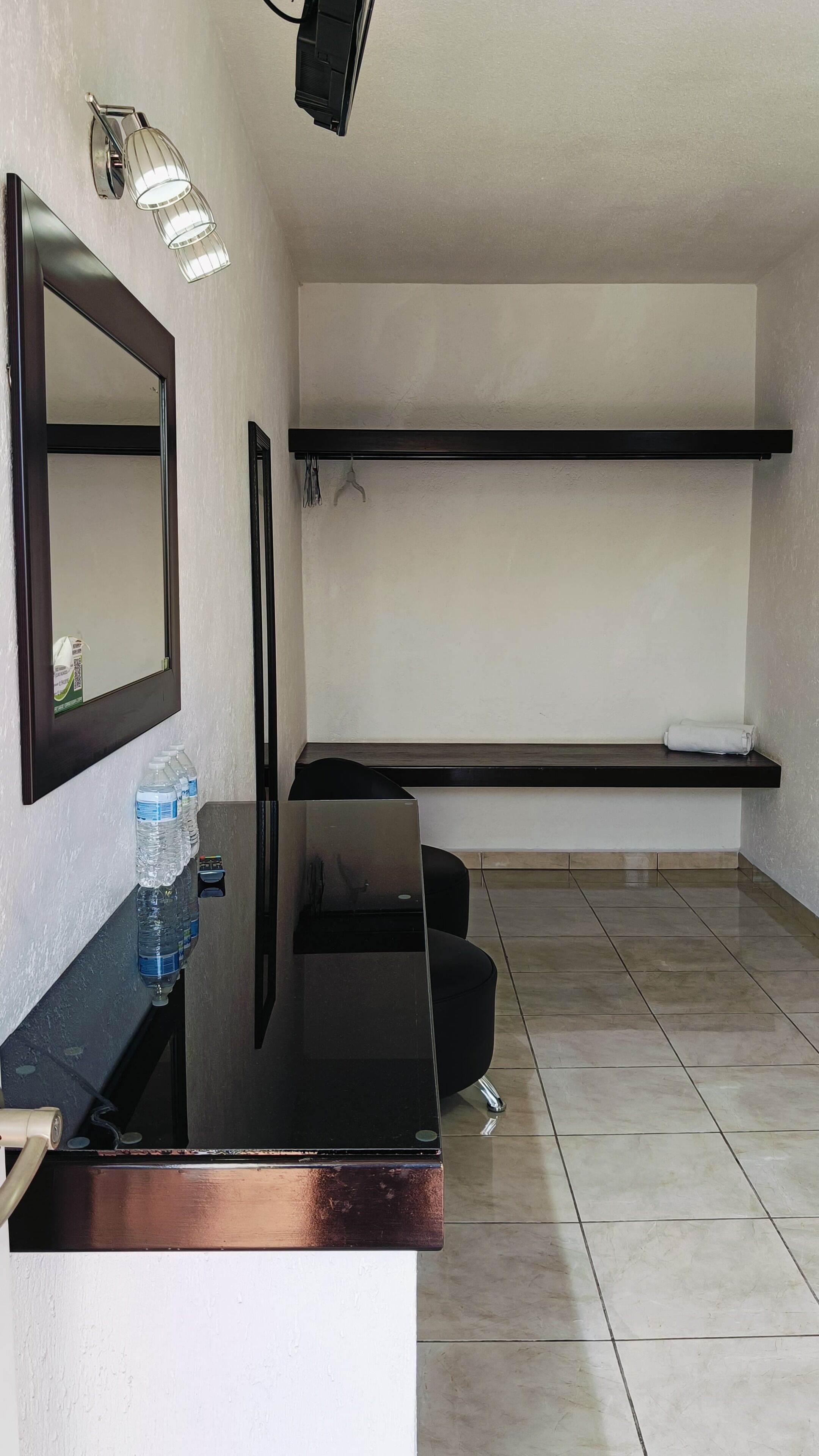 A modern bathroom with a black vanity, a mirror, a towel rack, and a shelf.