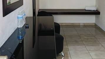 A modern bathroom with a black vanity, a mirror, a towel rack, and a shelf.