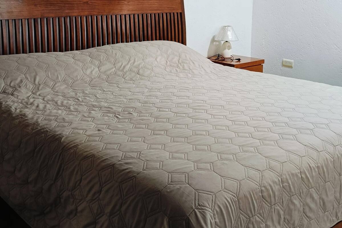 Een bed met een deken met een hexagonaal patroon en een houten hoofdbord.