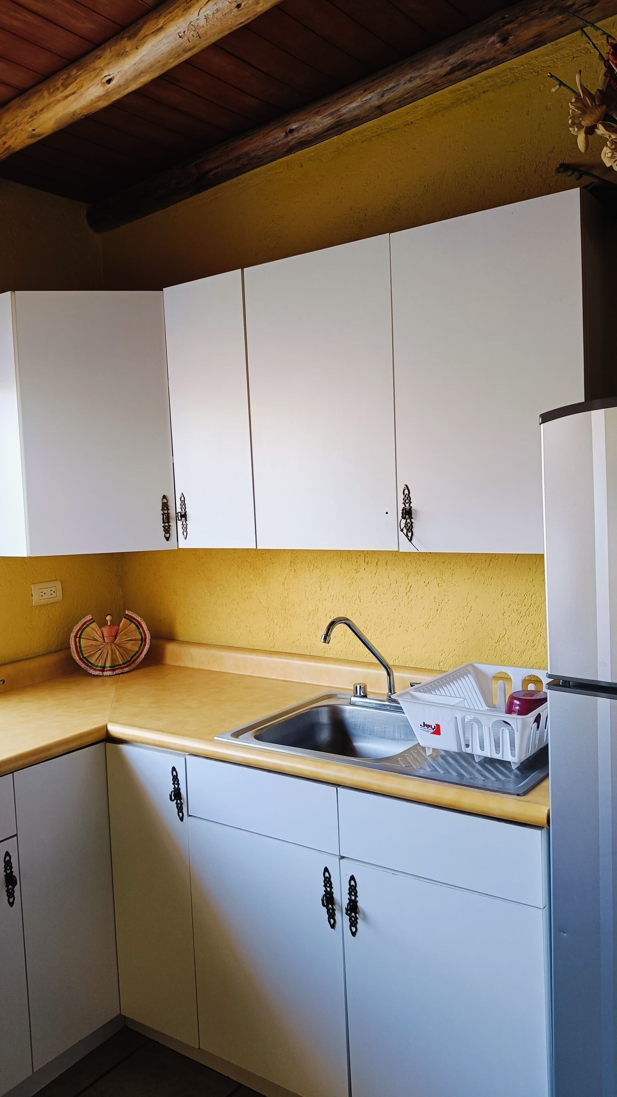 Una cocina con armarios blancos, un lavamanos y una encimera.