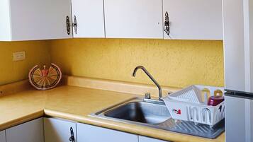Una cocina con armarios blancos, un lavamanos y una encimera.