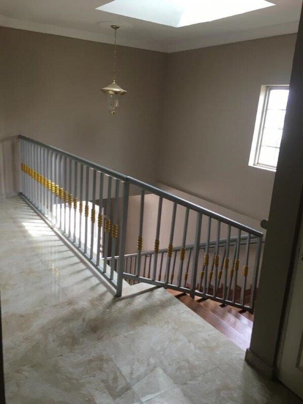 A spacious room with a high ceiling, a skylight, a metal railing, and a large window.
