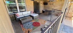 large covered patio, with couch, table, and tv overlooking pool