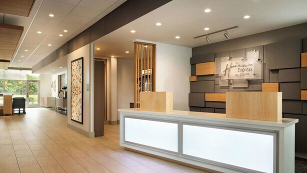 Een hotel receptie met een modern design, inclusief een receptiebalie, een wandbord en een houten scheidingswand.