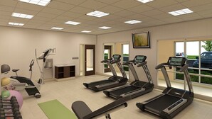 Een fitnessruimte met loopbanden, een hometrainer en een roeimachine.