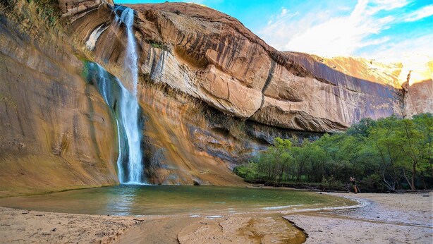 A waterfall cascading down a rocky cliff into a shallow pool, surrounded by greenery. - Red Rock Ranch Log Cabin: Large, Fully Furnished, 5 Bdr, sleeps 12, 3 levels (Escalante)