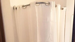 A bathroom with a white toilet, a white sink, and a white shower curtain.
