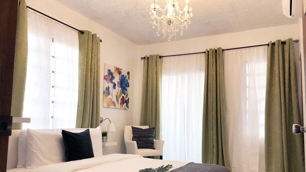 A bedroom with a bed, a desk, and a chair. There is a chandelier on the ceiling.