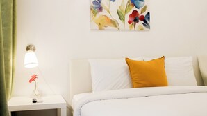 Una habitación de hotel con cama, mesita de noche con lámpara y un cuadro colgado en la pared.