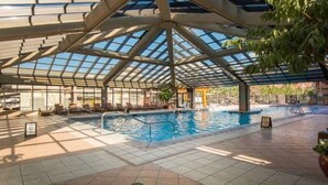 An indoor swimming pool with a glass ceiling, tiled floor, and lounge area with chairs. - Luxury Studio!! Gym, Pool, Sauna, Spa, Canyons Gondola Ski In/Out (Park City)