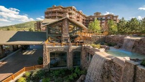 A lodge with a glass-enclosed upper level, a waterfall feature, and a stone facade. - Luxury Studio!! Gym, Pool, Sauna, Spa, Canyons Gondola Ski In/Out (Park City)