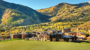 A resort with multiple buildings, a green field, and a mountainous backdrop. - Luxury Studio!! Gym, Pool, Sauna, Spa, Canyons Gondola Ski In/Out (Park City)