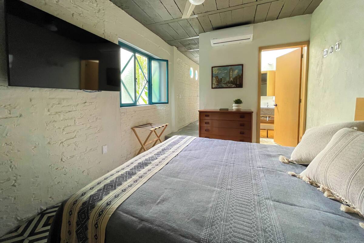 Een slaapkamer met een bed, een kaptafel, een raam en een deur.